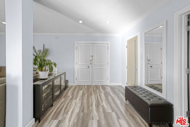 hall featuring a textured ceiling, light wood-type flooring, and ornamental molding