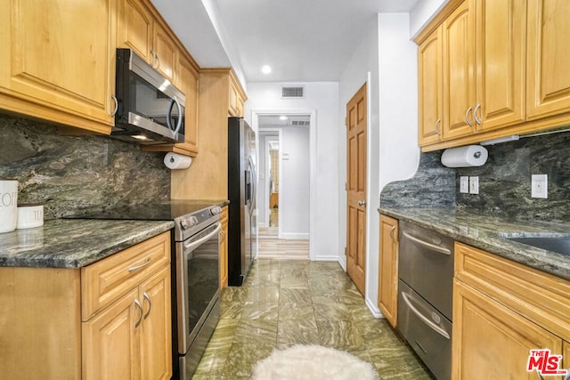 kitchen with decorative backsplash, appliances with stainless steel finishes, and dark stone countertops