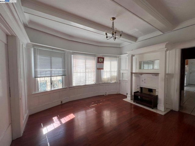 unfurnished living room with ornamental molding, a notable chandelier, beam ceiling, and dark wood-type flooring