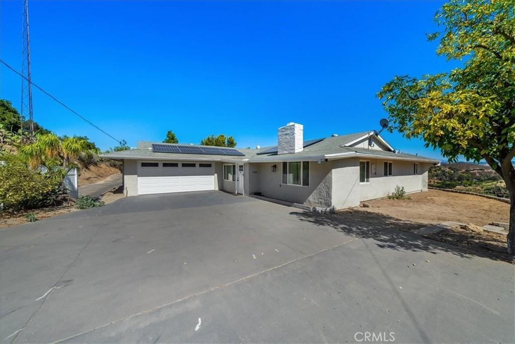 ranch-style house with a garage and solar panels