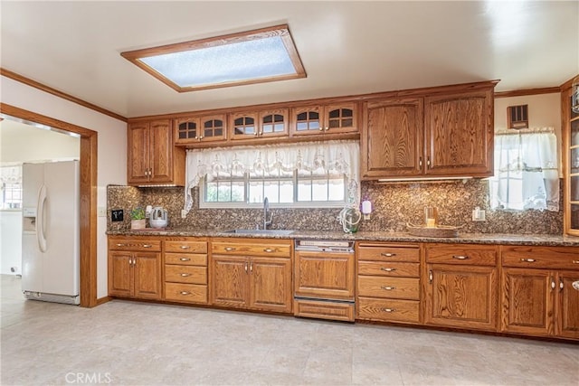 kitchen featuring paneled dishwasher, decorative backsplash, a skylight, sink, and white fridge with ice dispenser