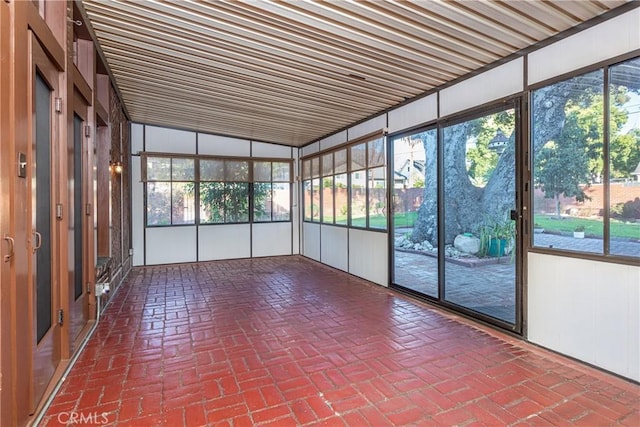 unfurnished sunroom featuring vaulted ceiling and a wealth of natural light