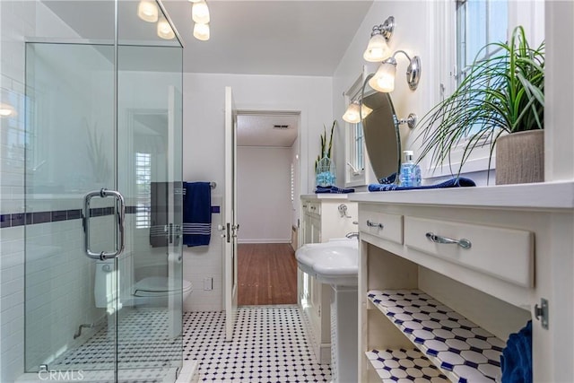 bathroom featuring toilet, tile walls, and a shower with shower door