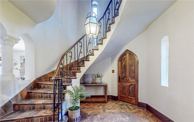 staircase featuring a high ceiling and ornate columns