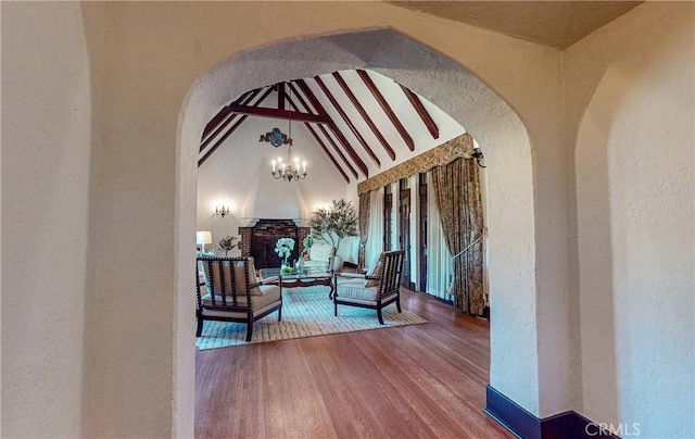 exterior space featuring a fireplace, wood-type flooring, lofted ceiling with beams, and a notable chandelier