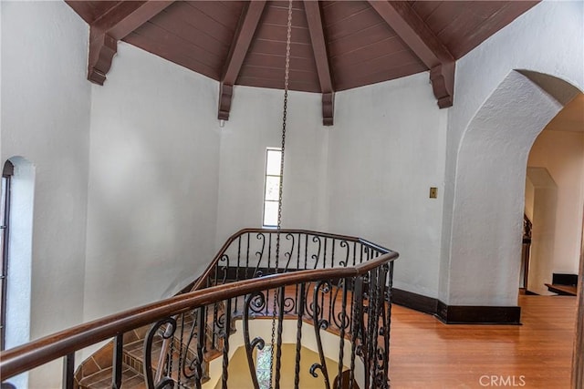 stairway with wooden ceiling, lofted ceiling with beams, and hardwood / wood-style flooring