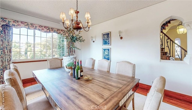 dining area with a chandelier, a textured ceiling, and light hardwood / wood-style flooring