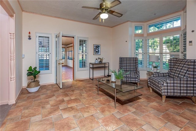 sitting room featuring ceiling fan, ornamental molding, a textured ceiling, and french doors