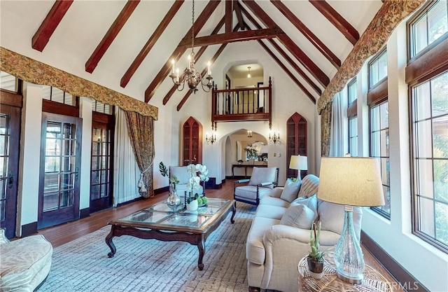 living room featuring beamed ceiling, hardwood / wood-style floors, high vaulted ceiling, and a notable chandelier