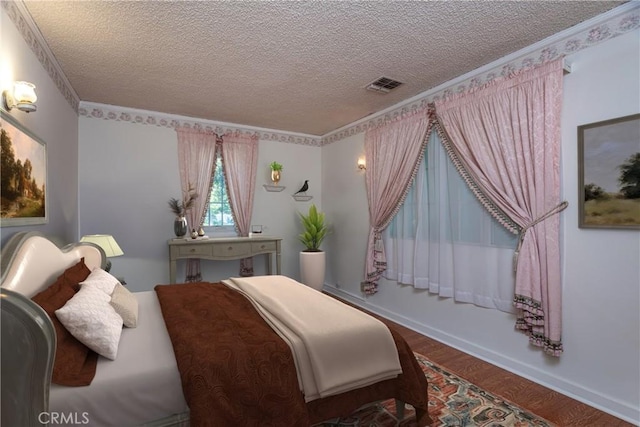 bedroom featuring crown molding, wood-type flooring, and a textured ceiling