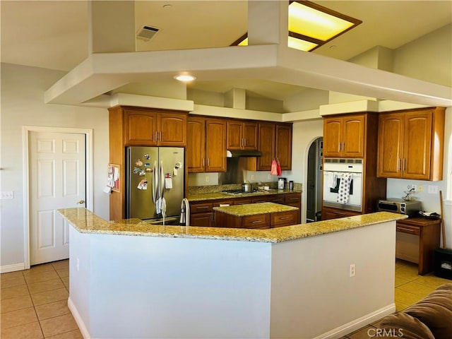 kitchen with a center island, light stone counters, high vaulted ceiling, light tile patterned floors, and appliances with stainless steel finishes