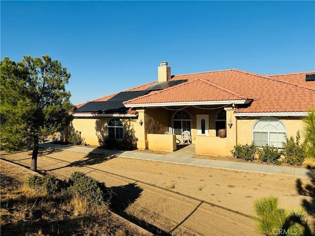 back of property with a porch and solar panels