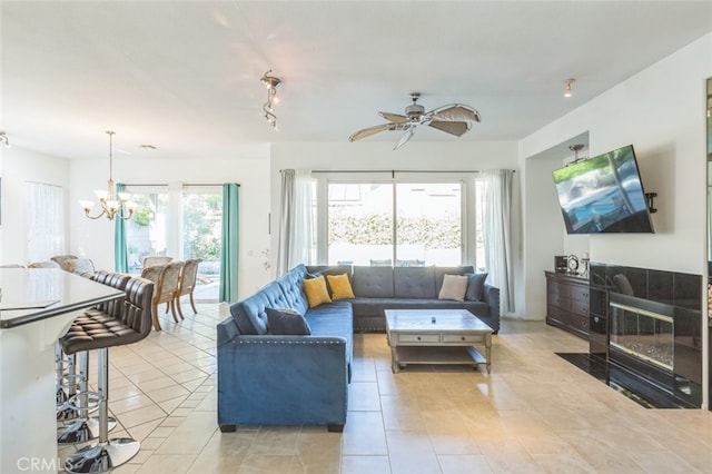 tiled living room with ceiling fan with notable chandelier