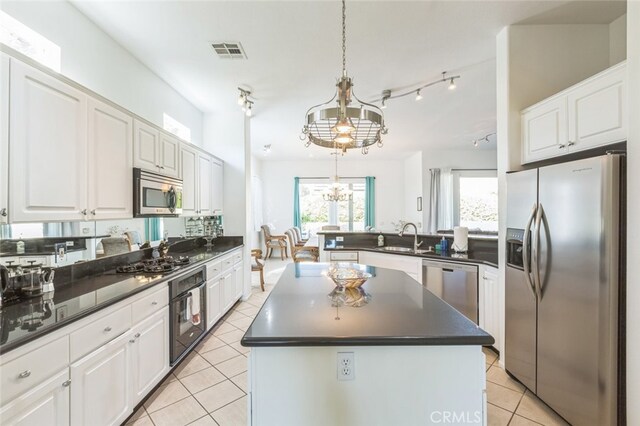 kitchen with a center island, a notable chandelier, white cabinets, hanging light fixtures, and stainless steel appliances