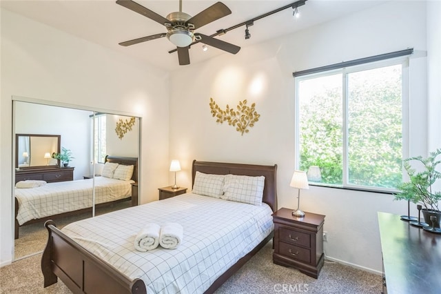 bedroom with ceiling fan, light carpet, multiple windows, and rail lighting