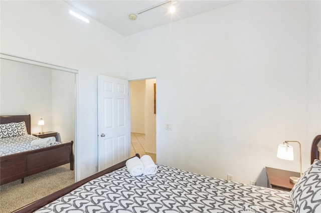 bedroom with light colored carpet, a closet, and rail lighting