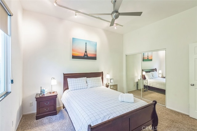 bedroom featuring a closet, ceiling fan, light colored carpet, and rail lighting