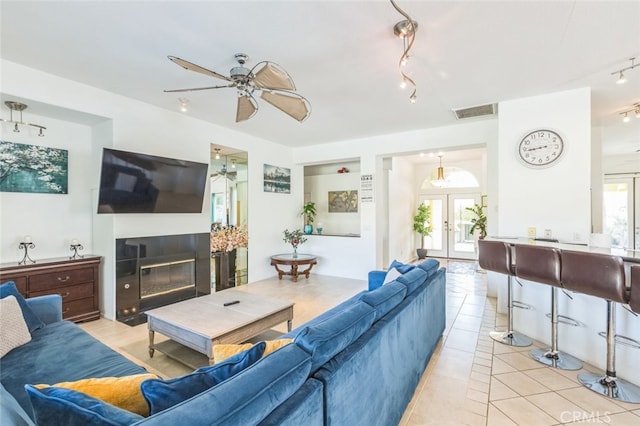 living room with rail lighting, light tile patterned flooring, ceiling fan, and french doors