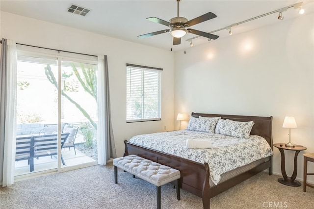 carpeted bedroom with multiple windows, access to outside, ceiling fan, and track lighting