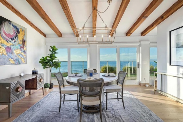 dining area featuring beamed ceiling, wood-type flooring, a water view, and a notable chandelier