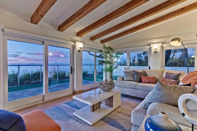 living room with wood-type flooring, lofted ceiling with beams, and a water view