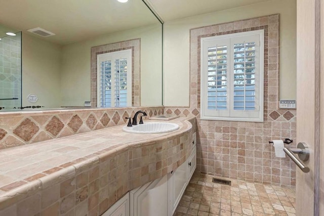 bathroom featuring vanity and tile walls