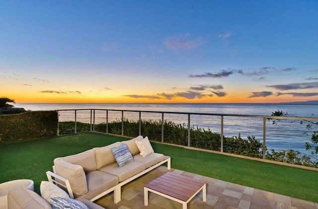 patio terrace at dusk with a lawn, a water view, and an outdoor hangout area