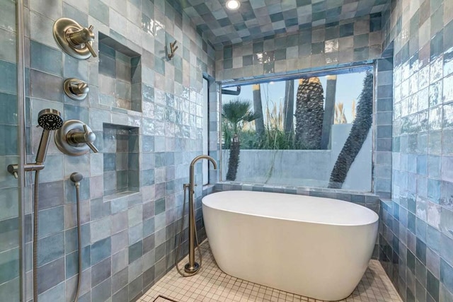 bathroom with tile patterned floors, a washtub, a healthy amount of sunlight, and tile walls