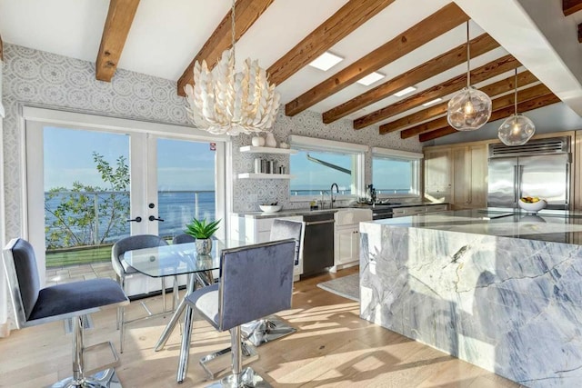 kitchen featuring decorative light fixtures, light hardwood / wood-style floors, a water view, and appliances with stainless steel finishes