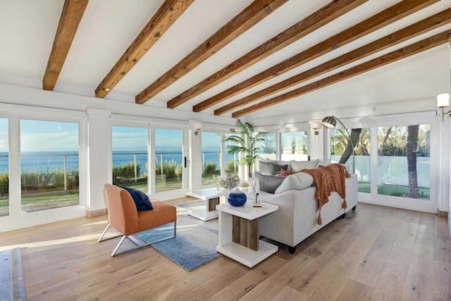 sunroom with lofted ceiling with beams and a water view