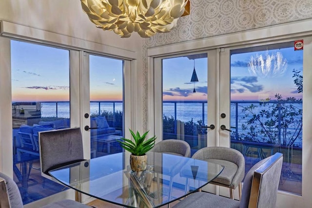 dining area with a chandelier, french doors, and a water view