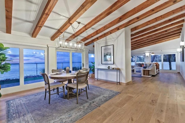 dining area featuring a notable chandelier, lofted ceiling with beams, a water view, and wood-type flooring