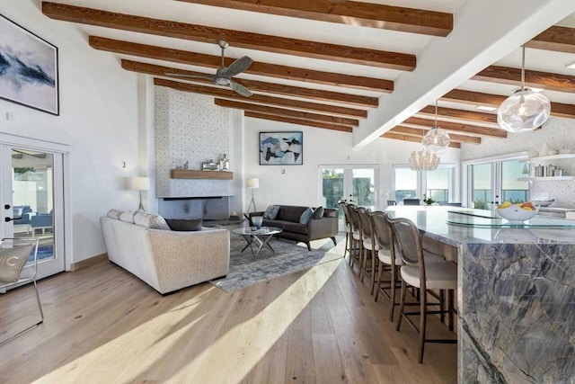 living room featuring french doors, lofted ceiling with beams, light hardwood / wood-style floors, and ceiling fan