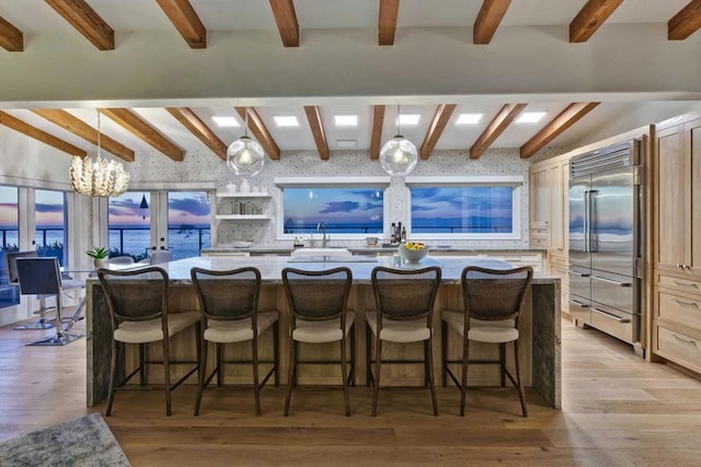 kitchen with french doors, light hardwood / wood-style flooring, built in refrigerator, decorative light fixtures, and a kitchen bar