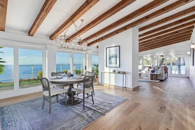 sunroom / solarium featuring vaulted ceiling with beams, a healthy amount of sunlight, a water view, and an inviting chandelier