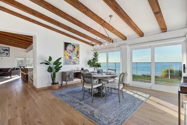 dining area featuring a healthy amount of sunlight, a water view, lofted ceiling with beams, and hardwood / wood-style flooring