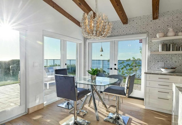 dining room featuring vaulted ceiling with beams, french doors, a chandelier, and light wood-type flooring