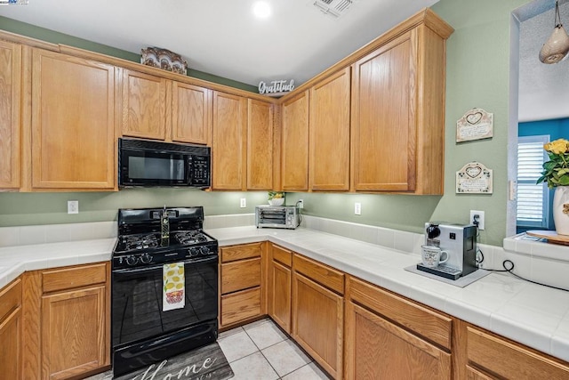 kitchen featuring tile countertops, light tile patterned flooring, and black appliances