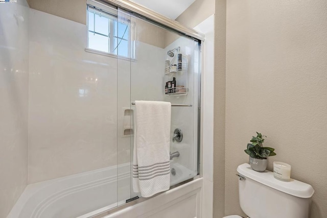 bathroom with toilet and shower / bath combination with glass door