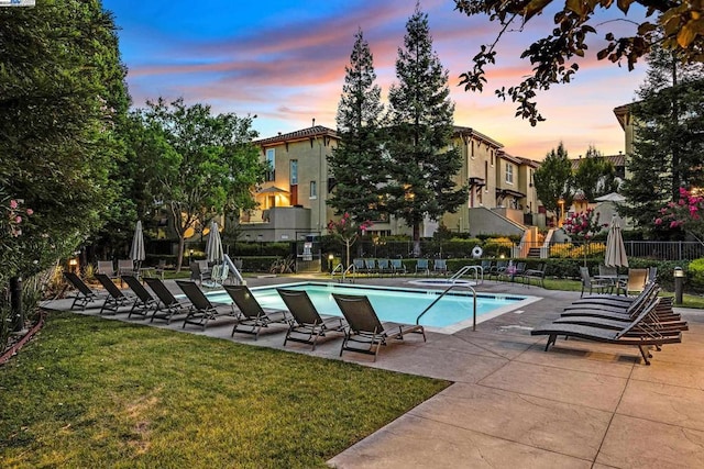 pool at dusk featuring a patio area and a yard