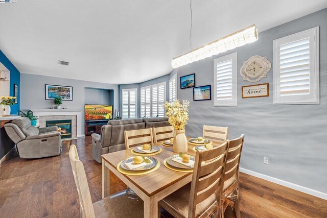 dining space with hardwood / wood-style floors and a tiled fireplace