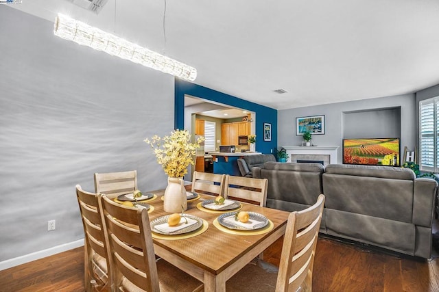 dining area with dark hardwood / wood-style flooring and a tile fireplace