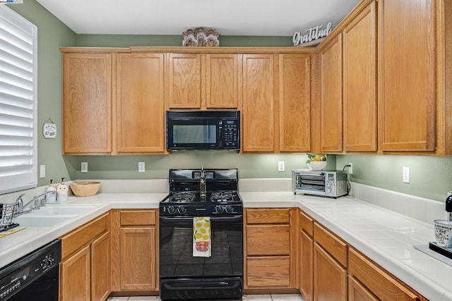 kitchen featuring tile countertops, sink, and black appliances