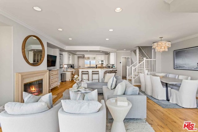 living room featuring an inviting chandelier, light hardwood / wood-style flooring, and ornamental molding