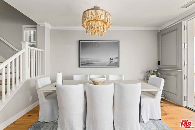 dining area featuring wood-type flooring, a notable chandelier, and crown molding