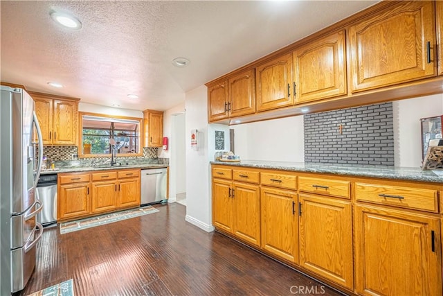 kitchen with backsplash, sink, dark hardwood / wood-style floors, a textured ceiling, and stainless steel appliances