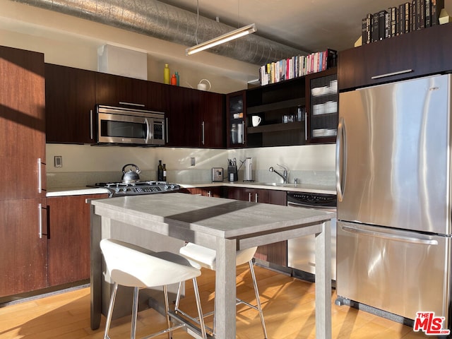 kitchen with dark brown cabinets, stainless steel appliances, light hardwood / wood-style floors, and sink