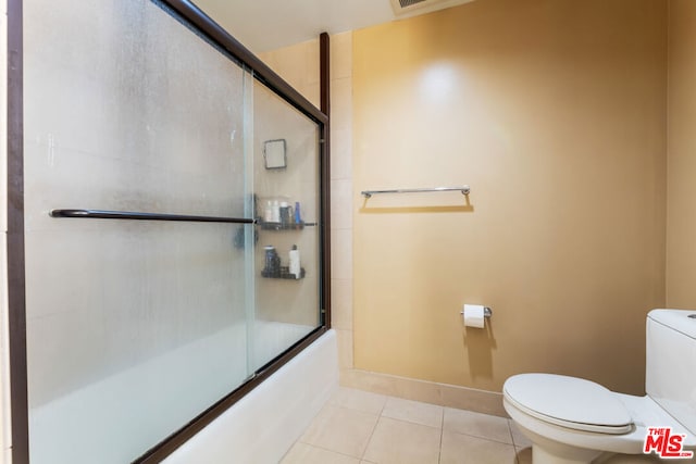 bathroom featuring bath / shower combo with glass door, tile patterned floors, and toilet