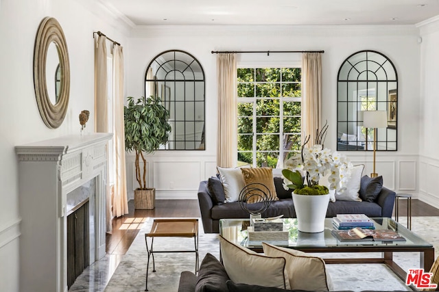 living room featuring wood-type flooring, a fireplace, and ornamental molding