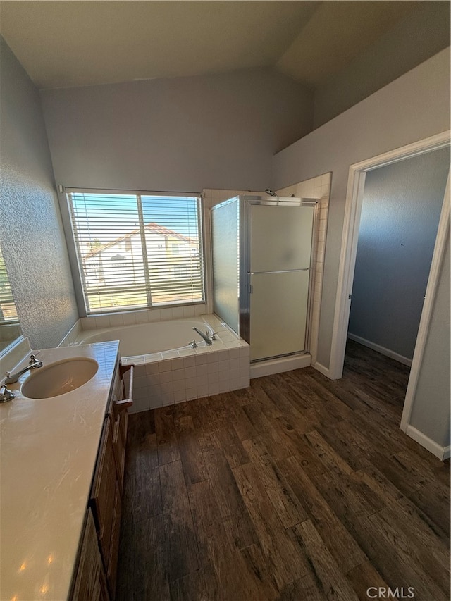 bathroom featuring hardwood / wood-style flooring, vanity, separate shower and tub, and vaulted ceiling